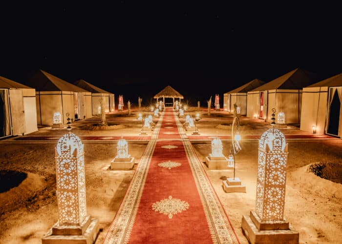 Luxury desert camp in Merzouga lit up at night with lanterns